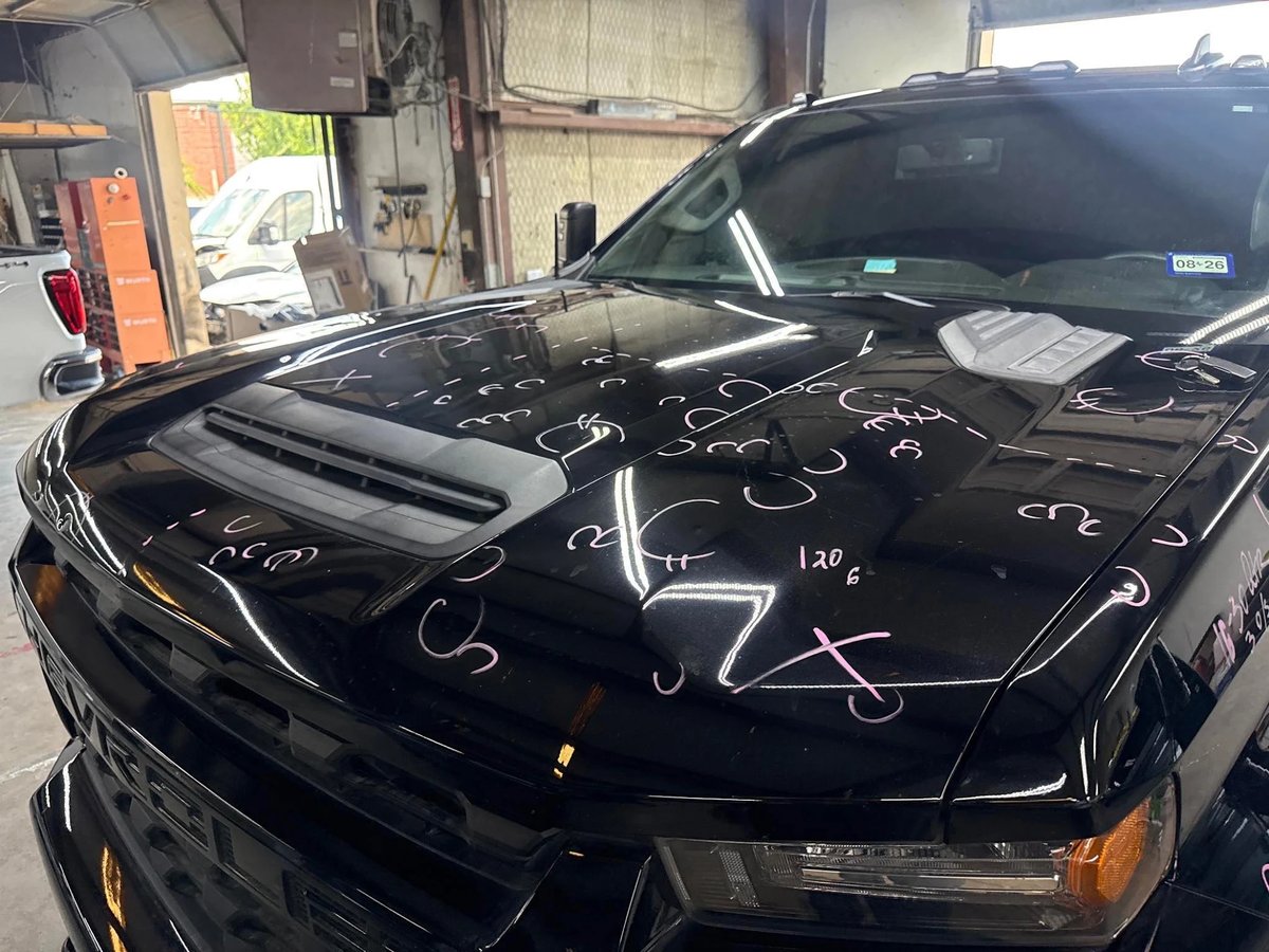Black Chevrolet 2500HD hood with hail dents marked in pink with a 120-dent count before PDR at DG Collision Center Lewisville TX