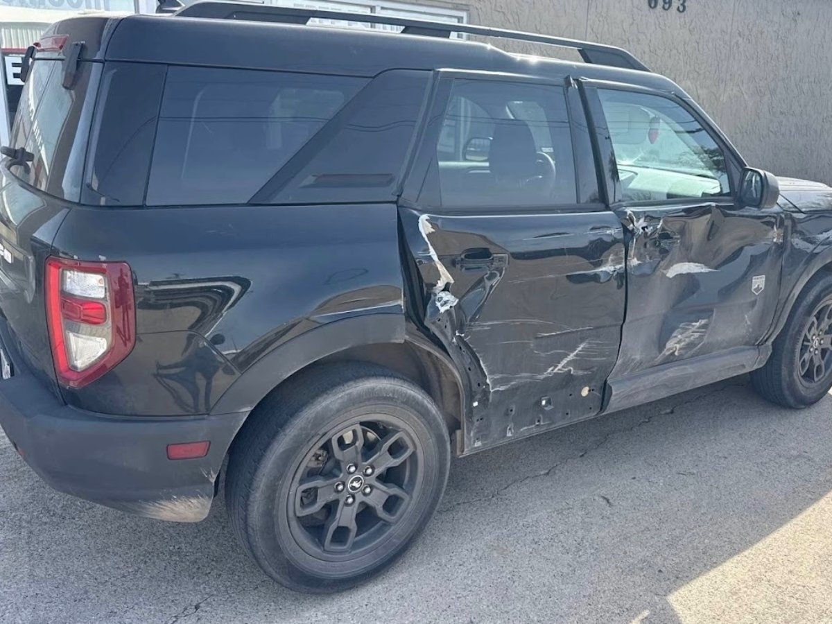 Side-impact damage before repair — crushed driver door on a Highland Village customer vehicle
